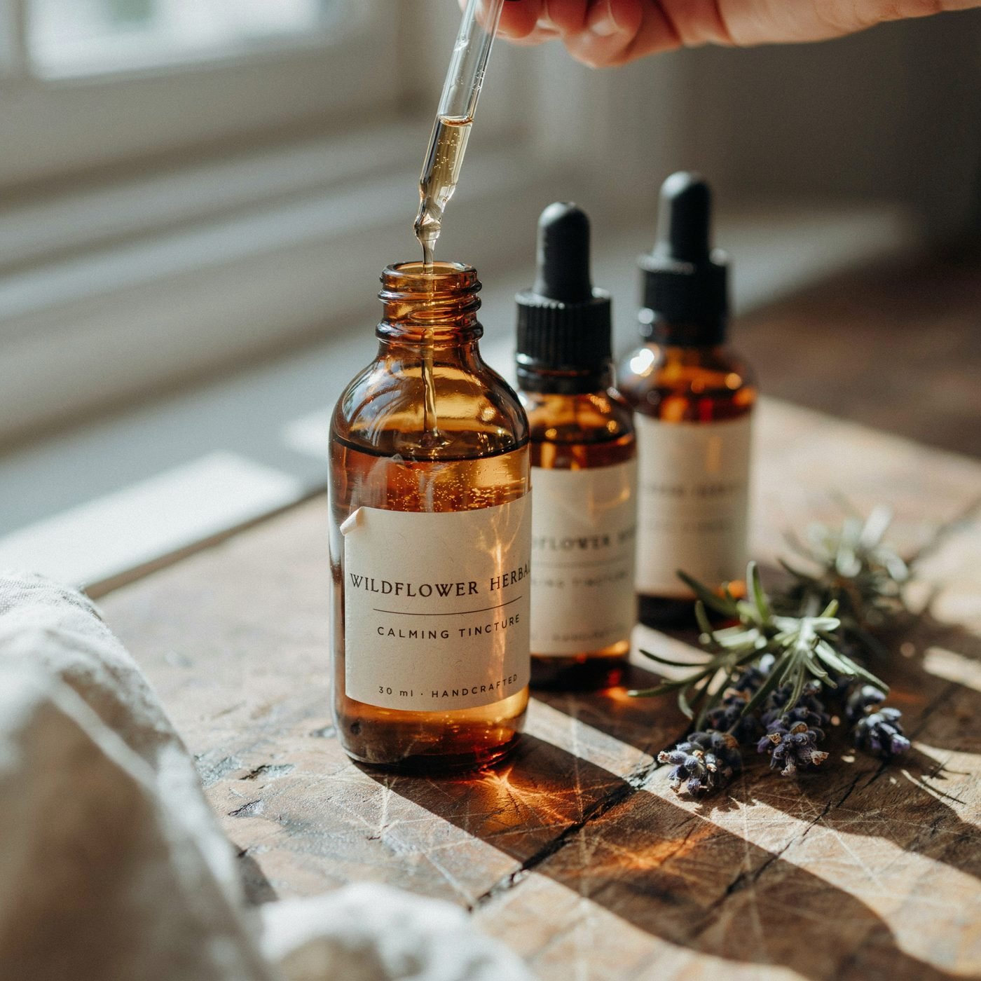 Amber glass tincture bottles with a dropper and lavender on a windowsill